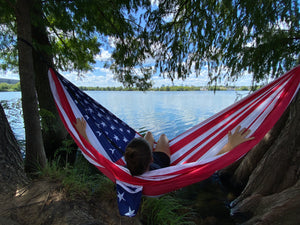 Co-founder, Amanda, sitting in the 'murica hammock that is hanging between two trees on the shore of Lady Bird Lake in Austin, TX